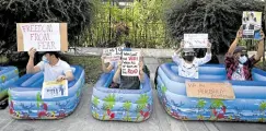  ?? —AFP ?? READY FOR WATER CANNONS Protesters hold up placards while sitting in inflatable kiddie pools during a demonstrat­ion against the coup in front of the Japanese embassy in Yangon on Feb. 10.