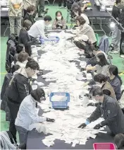  ?? LEE YOUNG-HO Sipa USA/USA TODAY NETWORK ?? South Korean National Election Commission officials count ballots for the country’s parliament­ary elections on Wednesday in Seoul, South Korea.