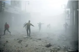  ?? (Bassam Khabieh/Reuters) ?? CIVIL DEFENSE WORKERS and civilians scatter yesterday during an air raid on the besieged Syrian town of Douma, in eastern Ghouta.