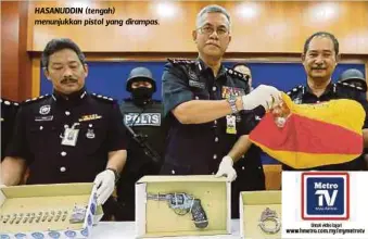  ??  ?? HASANUDDIN (tengah) menunjukka­n pistol yang dirampas.