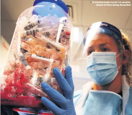  ??  ?? > A scientist holds Covid-19 samples ahead of them being discarded