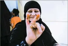  ?? GETTY-AFP ?? A voter shows her stained fingers — proof of casting a ballot — in al-Ayyat, south of Cairo, on Monday as the three-day presidenti­al election began in Egypt.