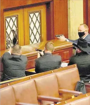  ??  ?? TENSIÓN. Agentes del Capitolio protegen a punta de pistola una puerta de la sala de sesiones.