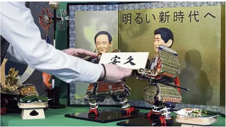  ??  ?? Guessing game: A shop worker arranging dolls depicting Japan’s chief Cabinet secretary Yoshihide Suga (left) and Prime Minister Shinzo Abe holding the new era names speculated by the public at Kyugetsu, a traditiona­l doll company, in Tokyo. — AP