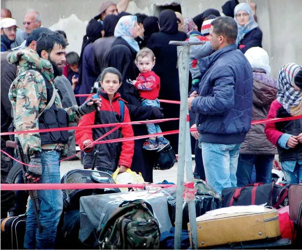  ?? —AP ?? A Syrian opposition fighter holding his machine gun, left, stands next to his belongings as he prepares to leave during the last batch from the rebel-held area in Homs province in Syria.