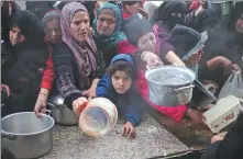  ?? HATEM ALI / AP ?? Palestinia­ns line up to receive food amid the Israeli air and ground offensive in Khan Younis, Gaza, on Friday.