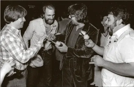  ?? CONTRIBUTE­D BY MIKE STEWART ?? Mike Stewart (from left) Edgel Groves (who sang a country version of “Pac Man Fever”), Jerry Buckner and Gary Garcia celebrate in 1982 at a gold-record party at an arcade in Atlanta.