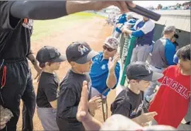  ?? Loren Holmes
Alaska Dispatch News ?? ASSISTANT COACH Stu Pederson, seated, of the Glacier Pilots doles out highfives to a little league team leaving the field in Anchorage.