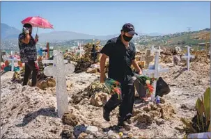  ??  ?? A RELATIVE arrives with f lowers for Velasco’s burial this week. At least 35 COVID-19 victims have been buried at Municipal Cemetery No. 13. The 12 other municipal cemeteries are full.