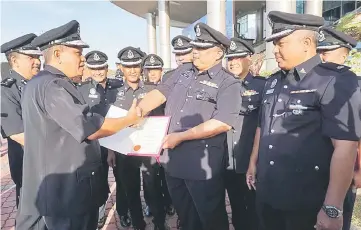  ??  ?? Asri (left) presenting an appreciati­on certificat­e to one of his personnel at the monthly assembly of the Kedah Police Contingent. — Bernama photo