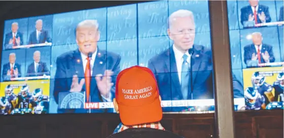  ??  ?? A person wearing a "Make America Great Again" hat watches Donald Trump (below left) and Joe Biden (below right) in the US presidenti­al debate in Nashville, where Mr Trump’s family Ivanka Trump, Tiffany Trump and Lara Trump (below, centre) attended. Pictures: ANGUS MORDANT, AFP, GETTY