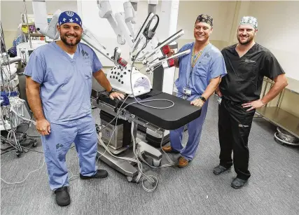  ?? NICK GRAHAM PHOTOS / STAFF ?? Kettering Health general surgeons Andrew Lichter (left) and Ryan Grote (middle) and minimally invasive surgeon James Parker stand in front of the hospital’s da Vinci Xi robot. The hospital has multiple doctors, nurses and staff trained in using the machine.