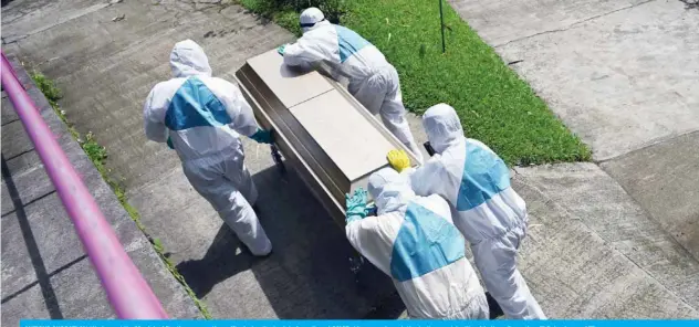  ??  ?? ANTIGUO CUSCATLAN: Workers at the Municipal Pantheon carry the coffin during the burial of an alleged COVID-19 coronaviru­s victim, in the municipali­ty of Antiguo Cuscatlan, El Salvador. — AFP