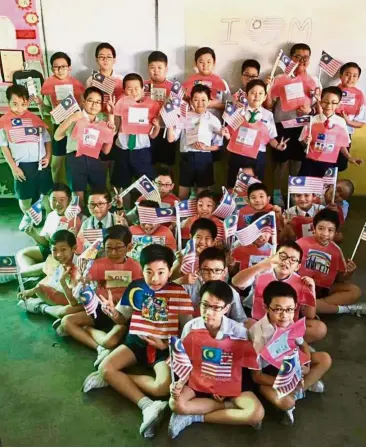  ??  ?? Patriotic youth: Pupils with mini Jalur Gemilang and wearing their decorated T-Shirt templates in Ipoh.