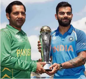  ??  ?? Dream final: India captain Virat Kohli (right) and his Pakistan counterpar­t Sarfraz Ahmed posing with the Champions Trophy yesterday ahead of the final today at the Oval in London. — AP