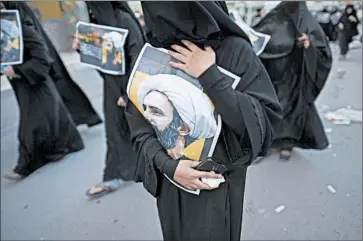  ?? MOHAMMED AL-SHAIKH/GETTY-AFP ?? Women in Bahrain hold portraits Sunday of Shiite Muslim cleric Nimr al-Nimr, whose execution in Saudi Arabia sparked tension between the Sunni kingdom and Shiite power Iran.