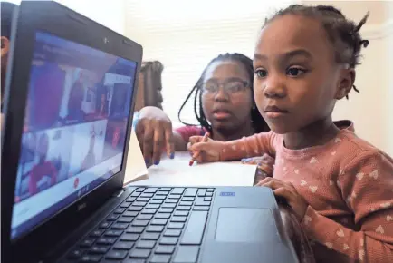  ?? SHAFKAT ANOWAR/AP ?? Lear Preston, 4, attends her Scott Joplin Elementary School virtual classes from home, assisted by her mother, Brittany, on Chicago’s South Side on Feb. 10. A “Betty” comic book from 1997 predicted virtual learning in 2021.