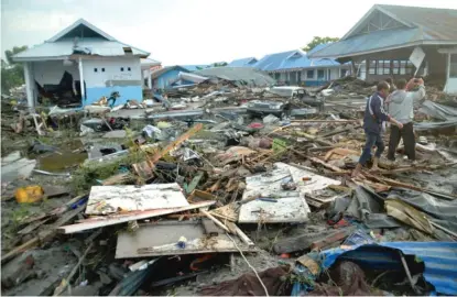  ?? RIFKI/AP ?? People survey the damage Saturday following earthquake­s and a tsunami in Palu, Indonesia.