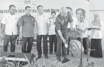  ?? — Gambar Bernama ?? SIMBOLIK: Najib memukul gong simbolik melancarka­n Model Baharu Lot Perumahan Generasi Baharu FELDA ketika dalam Lawatan Kerja ke Daerah Bera di FELDA Kumai, semalam. Turut hadir Adnan (dua kiri), Sabri (tiga kiri) dan Shahrir (tiga kanan).