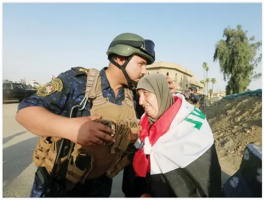  ??  ?? A member of Iraqi police kisses an old woman in Mosul on Sunday. (Reuters)