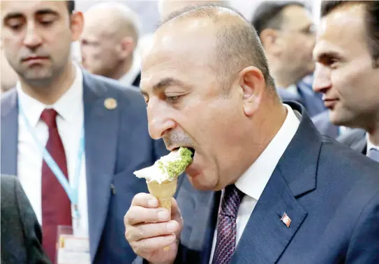  ??  ?? Turkey’s Foreign Minister Mevlut Cavusoglu eats ice cream during a visit to the Turkish booth at the tourism fair ITB in Berlin. (AP)