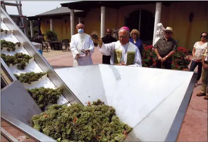  ?? WES BOWERS/NEWS-SENTINEL ?? Bishop Myron J. Cotta anoints Albarino grapes at St. Jorge Winery on Monday.