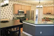  ??  ?? Maple cabinets with upper moldings frame the kitchen work space and the planning desk on the opposite wall.