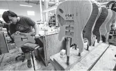  ?? Genaro Molina / TNS ?? Hunter Martin, 24, a lead stainer at Guitarwork­s, stains a Tom Anderson Cobra guitar at the company’s California headquarte­rs.