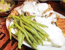  ??  ?? The large chicken-fried steak platter comes with two steaks, two sides, Texas toast and a salad at Richter's Antler Cafe in Spring Branch north of San Antonio.