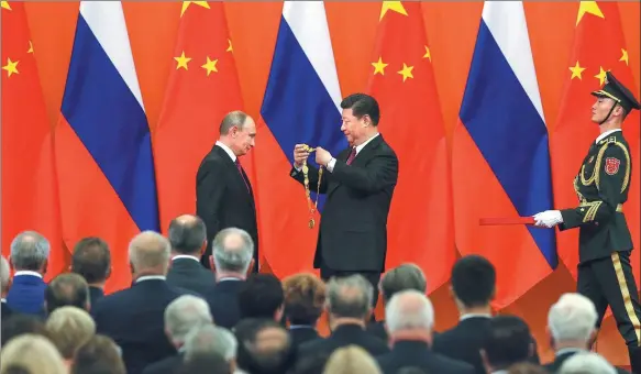  ?? XU JINGXING / CHINA DAILY ?? President Xi Jinping presents the first-ever Friendship Medal of the People’s Republic of China to Russian President Vladimir Putin at the Golden Hall of the Great Hall of the People in Beijing on Friday.