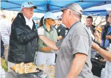  ?? A RELATED STORY IS ON PAGE A5. THE ASSOCIATED PRESS ?? President Donald Trump shakes hands as he meets with people affected by Hurricane Irma as he and first lady Melania Trump hand out food in Naples, Fla., on Thursday.