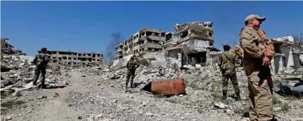  ?? - Reuters ?? ON GUARD: Members of Syrian forces of President Bashar Al Assad stand guard near destroyed buildings in Jobar, eastern Ghouta, in Damascus, Syria on April 2, 2018.