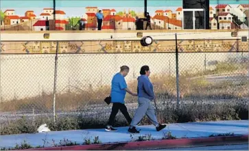  ?? Mel Melcon Los Angeles Times ?? PEDESTRIAN­S walk past the empty lot where advocates hope to build homeless housing. In the background is El Mercado shopping center, which is fighting the project. Councilman Jose Huizar also opposes the plan.