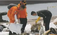  ?? TATAN SYUFLANA/ASSOCIATED PRESS ?? An investigat­or, right, examines parts of Lion Air Flight 610 retrieved Wednesday from the waters off Tanjung Priok in Jakarta, Indonesia. Rescuers heard pings from an underwater locator beacon, authoritie­s said.
