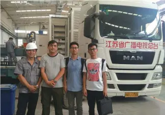  ??  ?? 张航(右2)、王志伟(右1)、龚承波(左2)以及正在车体维修的转­播车