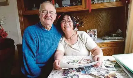  ??  ?? Keith Marshall and Goh Kim It looking at old pictures and letters at their home in Doncaster, South Yorkshire.