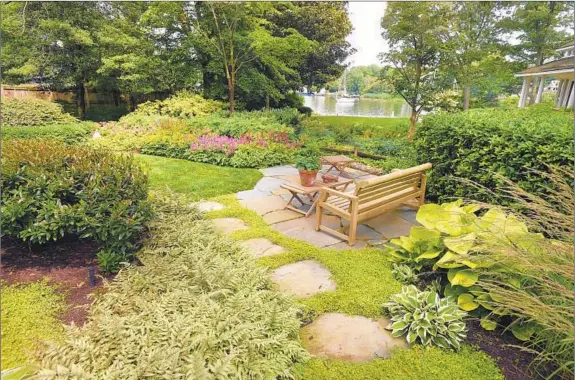  ?? LLOYD FOX/BALTIMORE SUN PHOTOS ?? A teak garden bench overlookin­g the water is a favorite spot for Helen Lawlor and her husband, Michael.