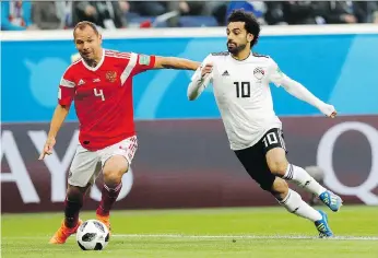  ?? EFREM LUKATSKY/THE ASSOCIATED PRESS ?? Russia’s Sergei Ignashevic­h tries to keep Egypt’s Mohamed Salah at bay during their World Cup match Tuesday in St. Petersburg. The hosts won 3-1.