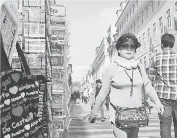  ??  ?? A tourist walks past a souvenirs for sale in Lisbon in November. Chinese applicants accounted for more than 80 per cent of the 1,526 resident permits issued under Portugal’s golden visa programme last year.