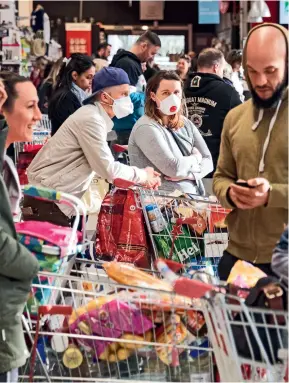  ??  ?? Le 16 mars 2020, à Pfastatt, dans le Haut-Rhin, les gens font leurs courses dans les supermarch­és.