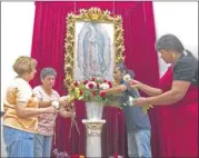  ??  ?? From left: Maria Elena Ramirez, Frances Martinez Manuel Lopez and Fausta Cornejo, place a flower arrangemen­t in front of an image of Our Lady of Guadalupe inside of Cristo Rey Catholic Church in East Austin.