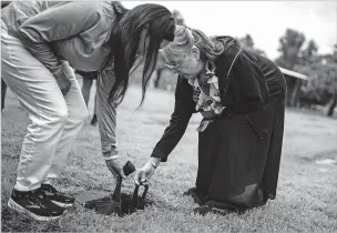  ?? SALWAN GEORGES/WASHINGTON POST FILE PHOTO ?? Rachel Twitchell-Justiss, left, and Martha Sara Jack place the brain of their relative Mary Sara, a young Sami woman who died of tuberculos­is in Alaska in 1933, into a grave in August after the Smithsonia­n Institutio­n returned it to their family.