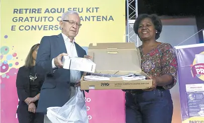  ??  ?? Juarez Quadros, da Anatel e Gired, entrega kit número 430 mil à beneficiár­ia do Bolsa Família Ivonete Brito