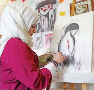  ??  ?? ↑ Top: Syrian cartoonist Amani Al Ali works on a painting in her home studio in the city of Idlib.