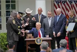  ?? Evan Vucci/Associated Press ?? President Donald Trump hands out a pen after signing an executive order on police reform on Tuesday in the Rose Garden of the White House in Washington.