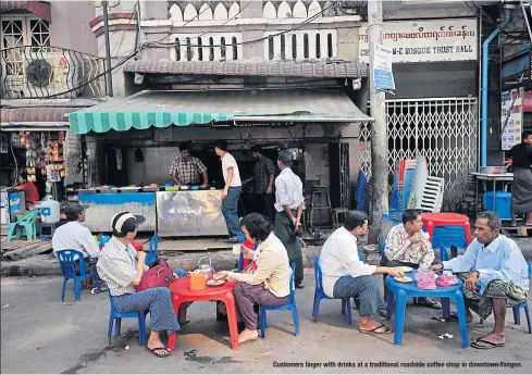  ??  ?? Customers linger with drinks at a traditiona­l roadside coffee shop in downtown Yangon.