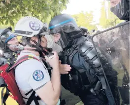  ?? LEWIS JOLY/AP ?? Police officers in riot gear confront a first aid volunteer Sunday at a May Day demonstrat­ion in Paris. Protesters demanded that government do more to help workers.