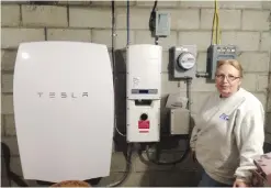  ??  ?? MIDDLETOWN SPRINGS: In this photo, Rhonda “Honey” Phillips poses next to a Tesla Powerwall battery and inverter connected to a solar panel array in her yard in Middletown Springs, Vermont. —AP