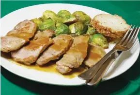  ?? LINDA GASSENHEIM­ER/TNS ?? Whiskey Mustard-Crusted Pork with Balsamic Glazed Brussels Sprouts.