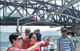  ?? PAN YULONG / XINHUA FRED DUFOUR / FOR CHINA DAILY ?? Top: Dandong residents visit the trade zone on October 15, 2015, the day it opened for business.Above: Tourists view the DPRK from the Yalu River in Dandong.